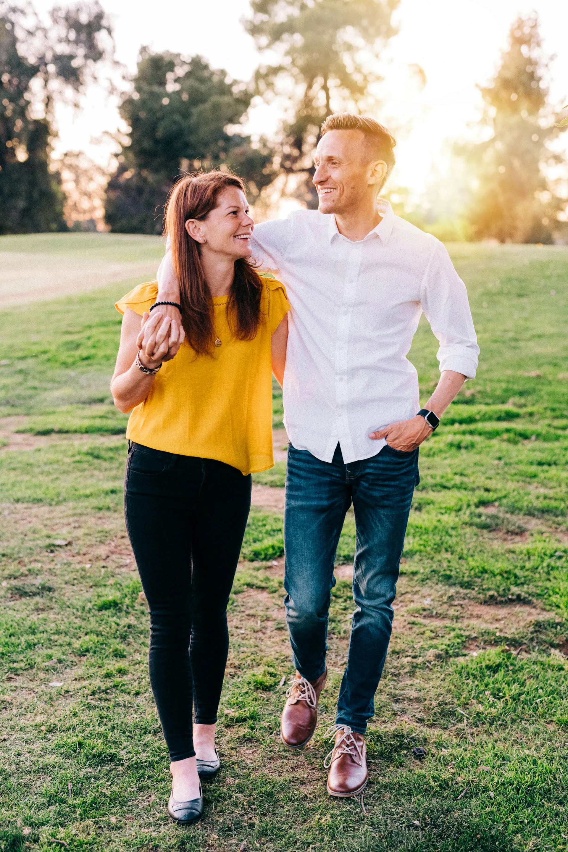 Un homme et une femme d'une trentaine d'années se sourient en marchant dans un parc au soleil couchant